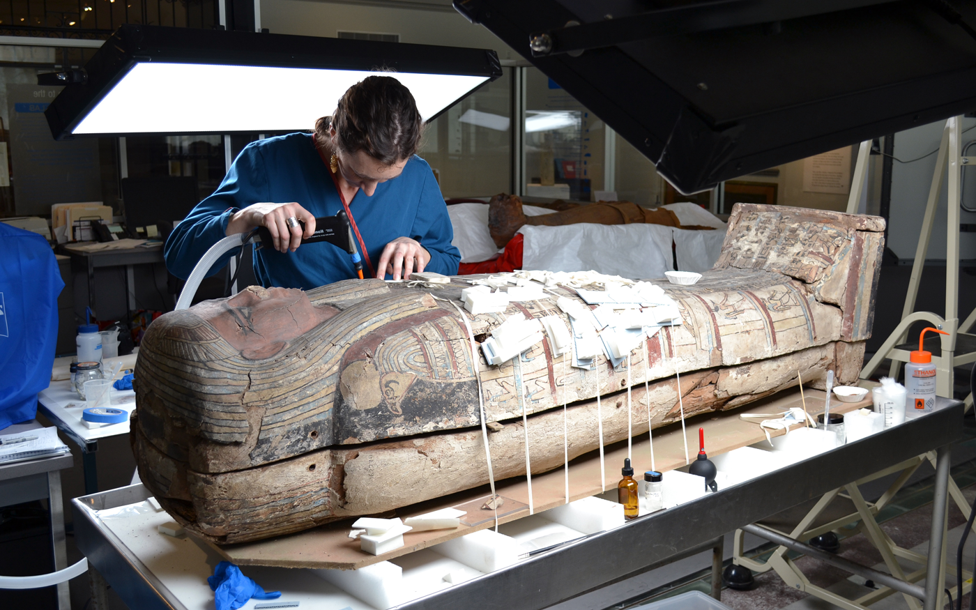 A conservator working on a sarcophagus.