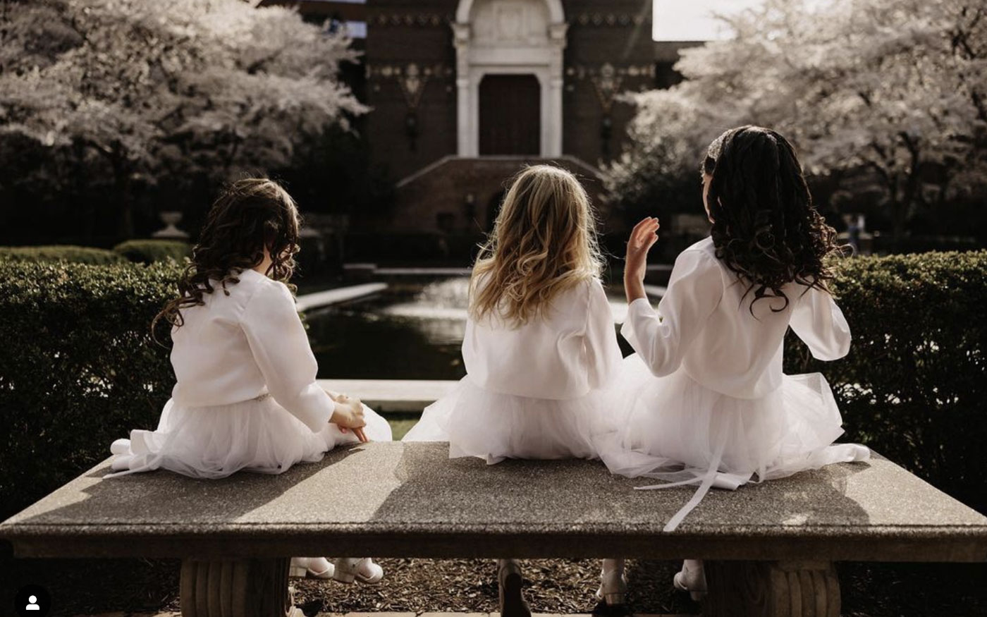 Three flower girls sitting on a bench in the Warden Garden.