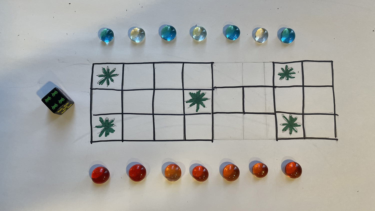A paper board game with a die and two sets of stones