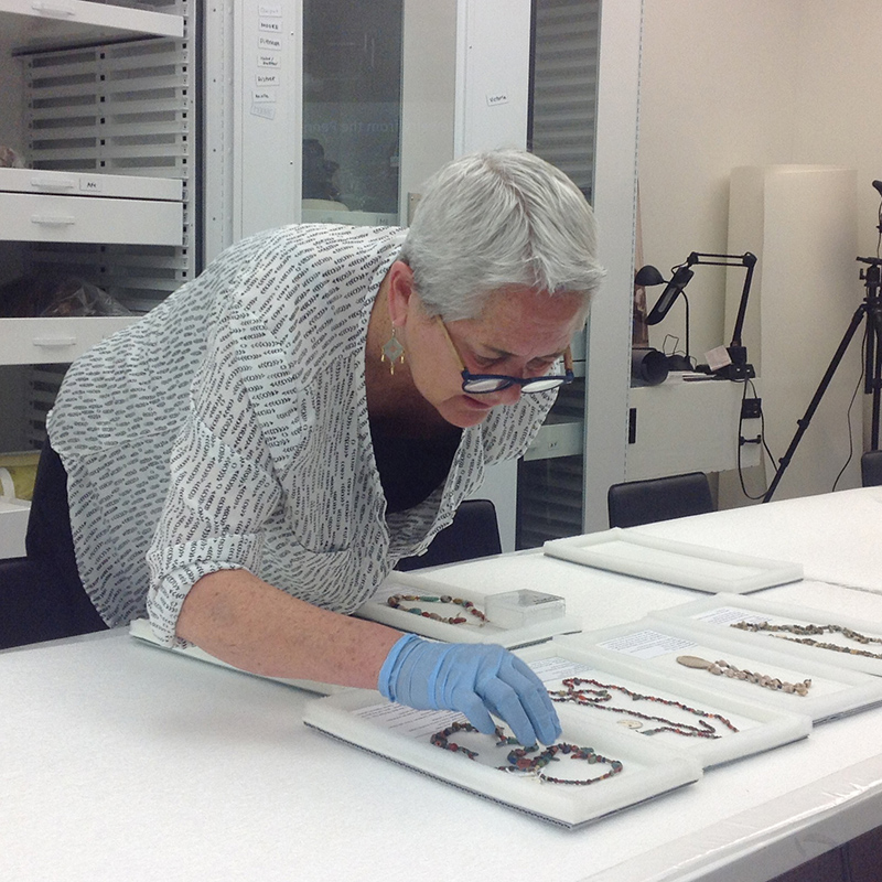 Jane Hickman examining beaded jewelry.