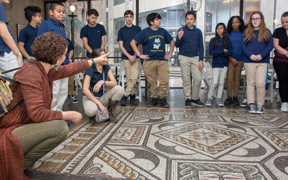 A class learning about a floor mosaic.