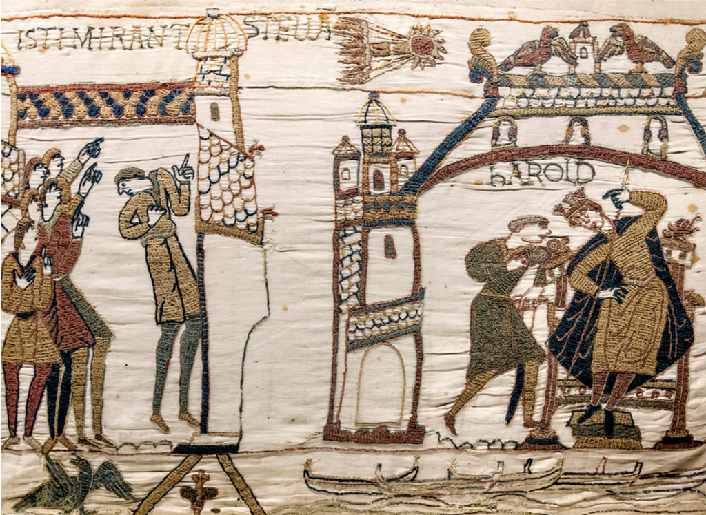 Close up of an embroidered tapestry showing village people in awe of a comet in the sky
