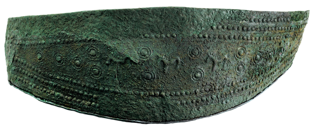 Lozenge shaped bronze belt with geometric patterns of bosses and lines are supplemented with images of sundisks and rays, horses, and dancing men