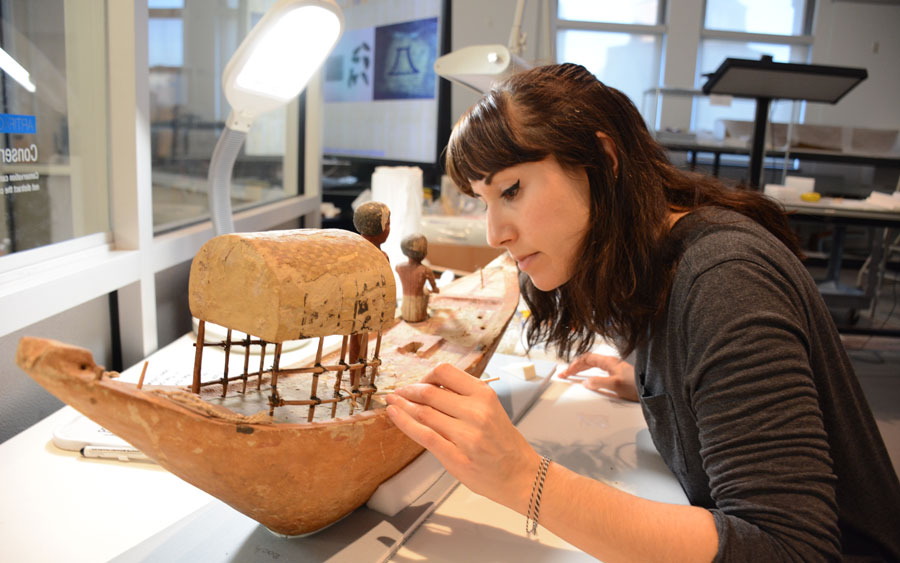 Conservator cleaning and restoring an artifact.