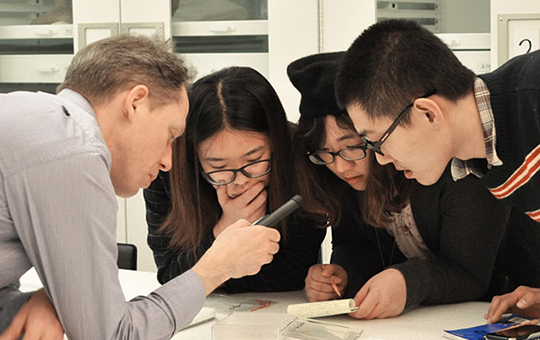 A group of students examining an object with a researcher.